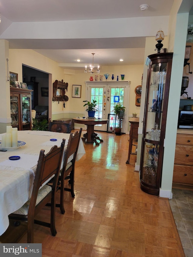 dining space featuring parquet floors, french doors, and a notable chandelier