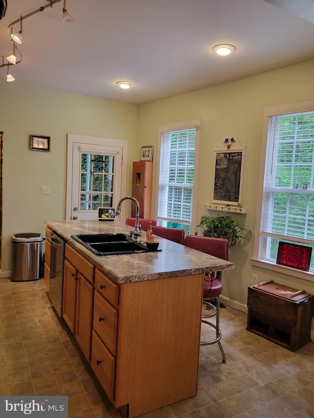 kitchen featuring a kitchen bar, sink, dishwasher, and an island with sink