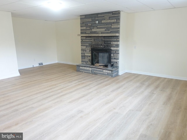 unfurnished living room featuring a drop ceiling, a fireplace, and light hardwood / wood-style flooring