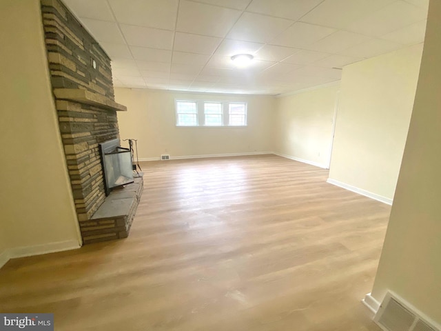 unfurnished living room with a stone fireplace and light wood-type flooring