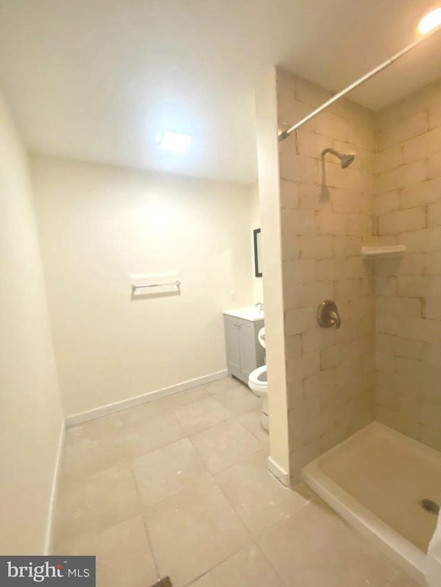 bathroom featuring tile patterned flooring, vanity, toilet, and tiled shower