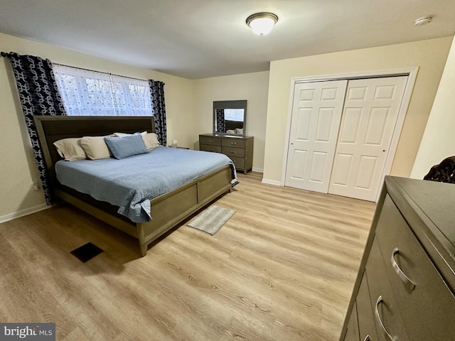 bedroom with multiple windows, a closet, and light wood-type flooring