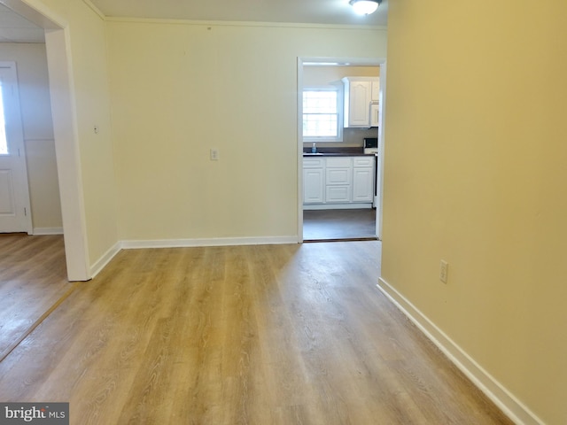 spare room featuring crown molding and light hardwood / wood-style floors