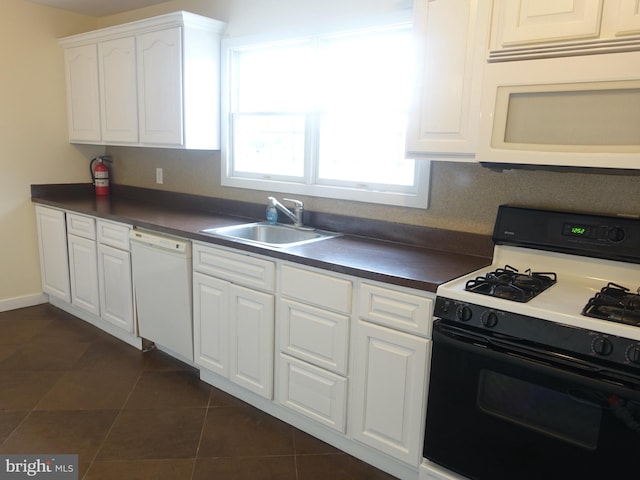 kitchen with white cabinetry, sink, dark tile patterned flooring, and white appliances