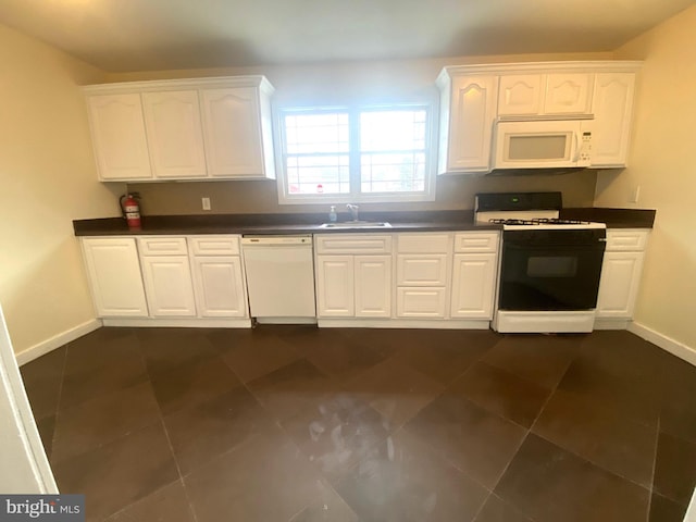 kitchen featuring sink, white cabinets, dark tile patterned flooring, and white appliances