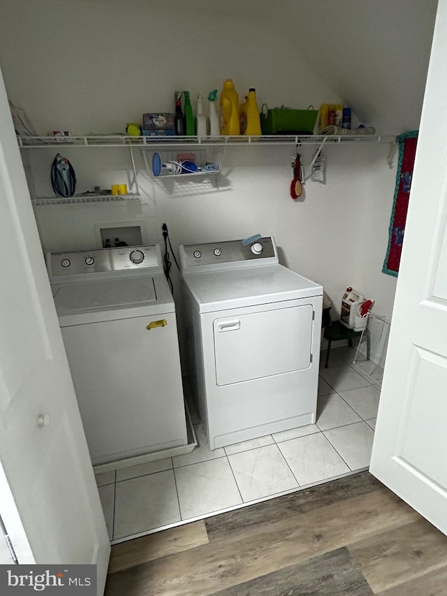 clothes washing area with light hardwood / wood-style flooring and washing machine and clothes dryer