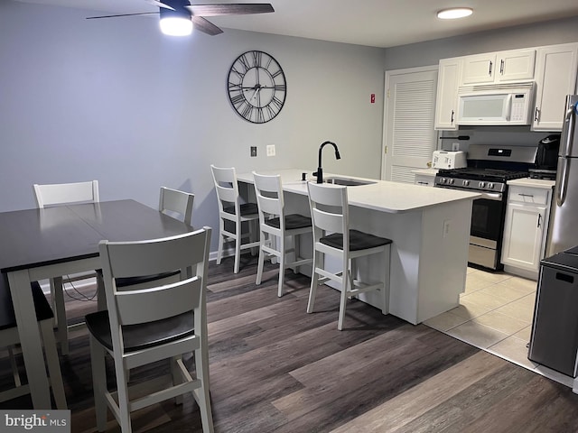 kitchen featuring appliances with stainless steel finishes, white cabinetry, light hardwood / wood-style flooring, and a kitchen breakfast bar