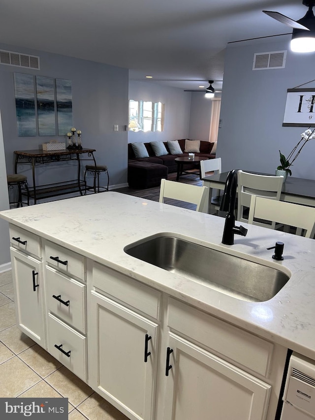 kitchen with ceiling fan, light stone countertops, sink, and light tile patterned floors