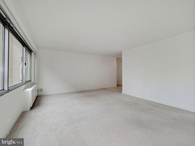 empty room featuring light carpet and radiator heating unit