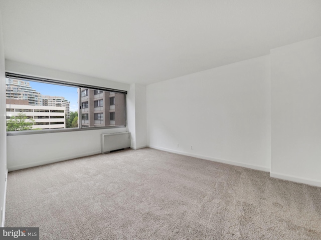 unfurnished room featuring radiator heating unit and carpet