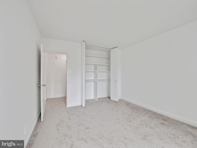 unfurnished bedroom with light carpet and a closet