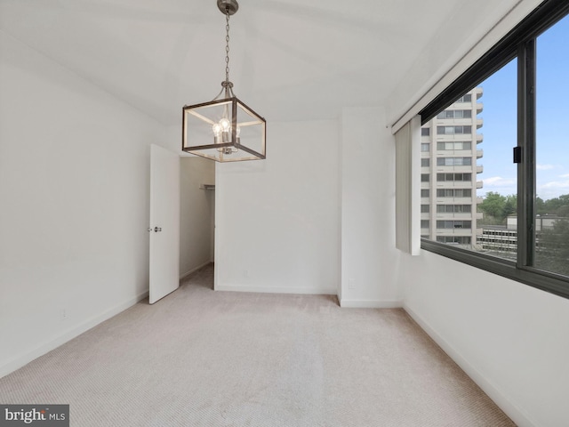 spare room with light carpet and a chandelier