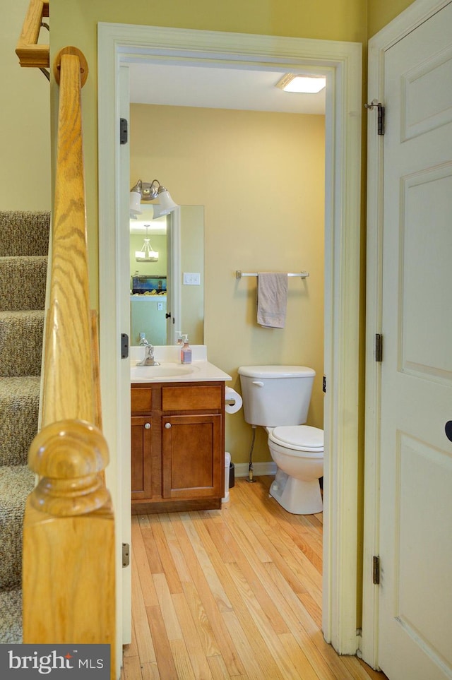 bathroom with toilet, hardwood / wood-style flooring, and vanity