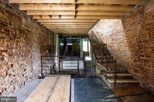 interior space with beam ceiling, wood-type flooring, and brick wall