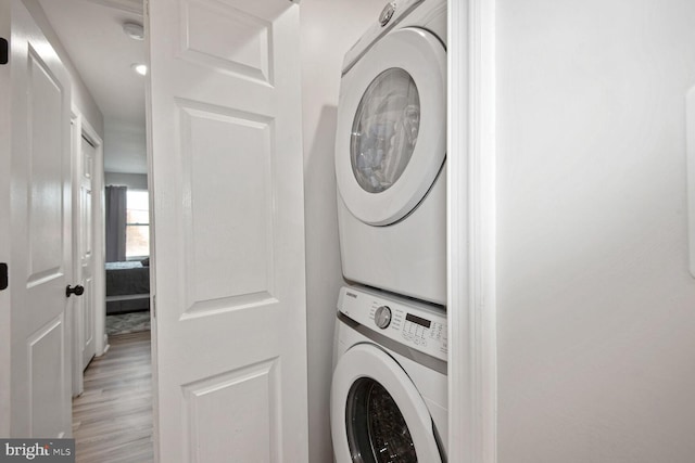 laundry room featuring stacked washing maching and dryer and light wood-type flooring