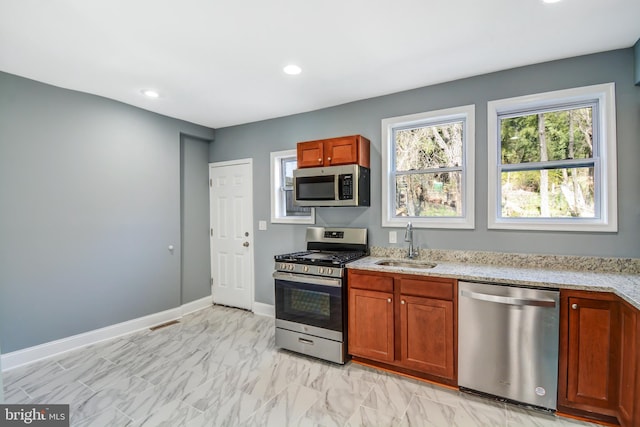 kitchen with sink, light stone countertops, light tile floors, and stainless steel appliances