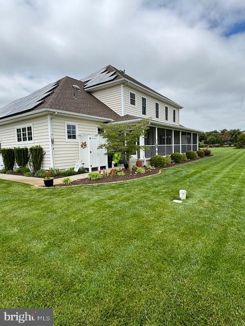 exterior space featuring a sunroom, solar panels, and a yard