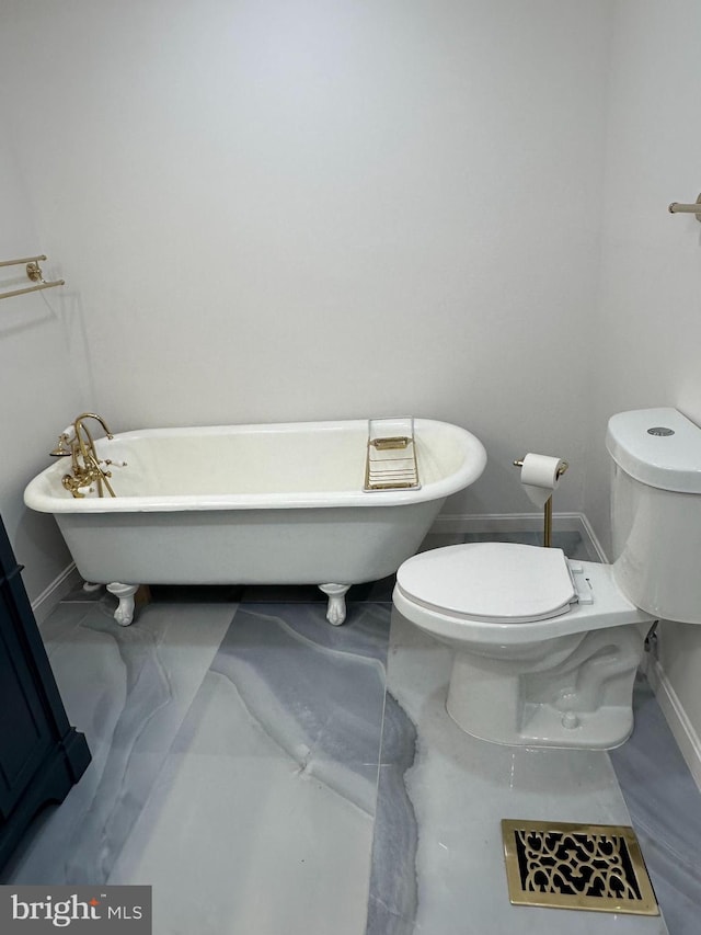 full bath with marble finish floor, a freestanding tub, toilet, and baseboards