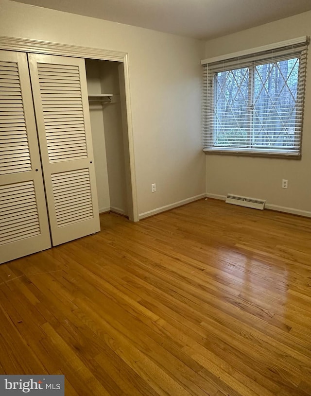 unfurnished bedroom with a closet, wood finished floors, visible vents, and baseboards