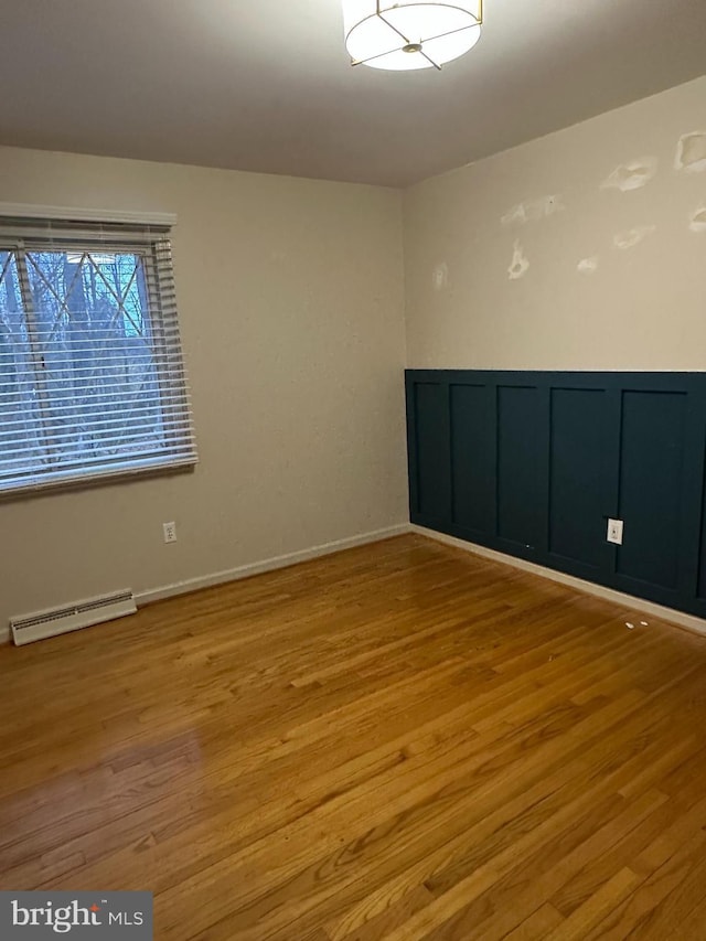 empty room featuring wainscoting, visible vents, and light wood-style flooring