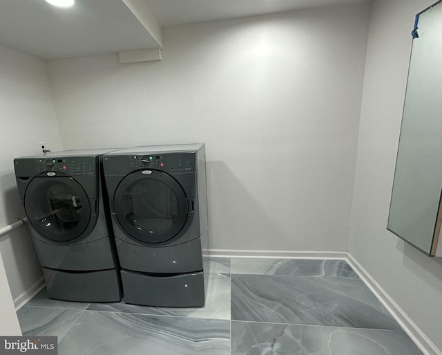 clothes washing area with laundry area, baseboards, marble finish floor, and washing machine and clothes dryer