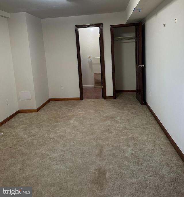 unfurnished bedroom with carpet floors, a closet, visible vents, ensuite bath, and baseboards