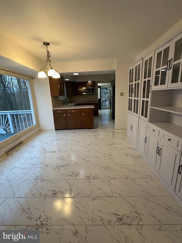 kitchen with pendant lighting, sink, black refrigerator, white cabinetry, and dark brown cabinets