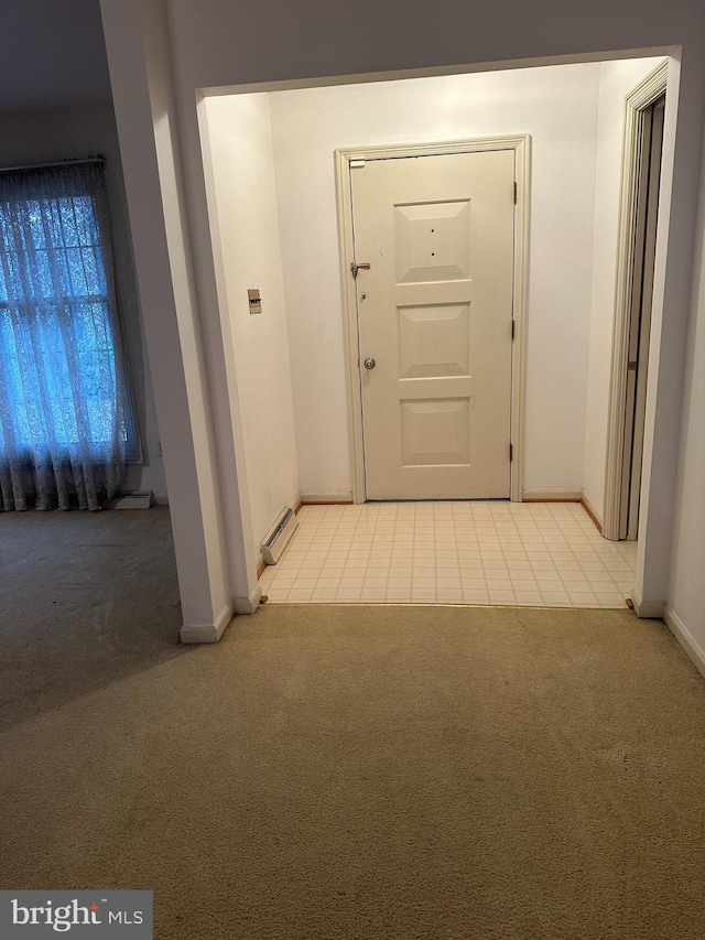 interior space with light carpet, a baseboard radiator, and baseboards