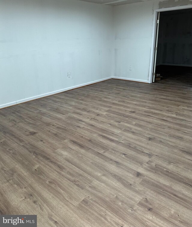 empty room featuring dark wood-style floors and baseboards