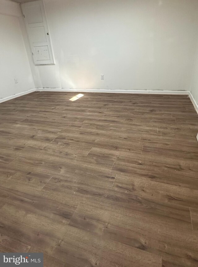 spare room with baseboards and dark wood-style flooring