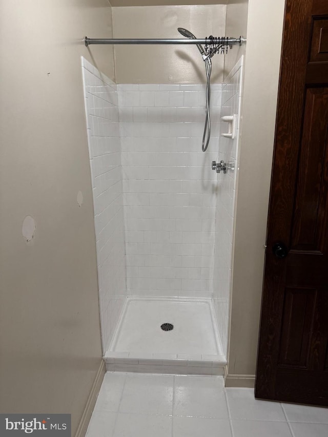 bathroom with a stall shower, baseboards, and tile patterned floors