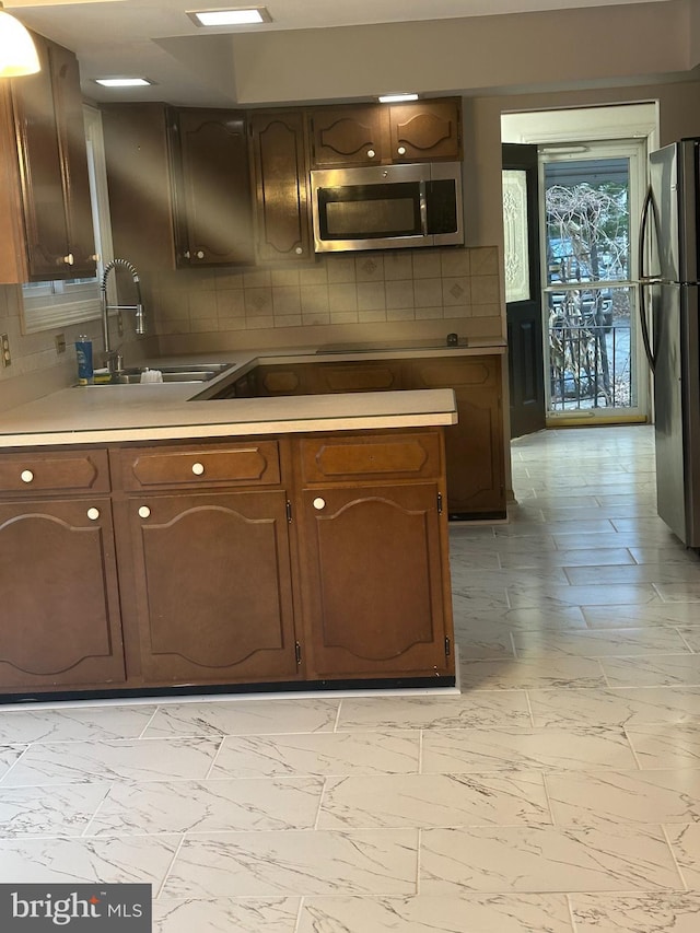 kitchen with stainless steel appliances, marble finish floor, light countertops, and a sink