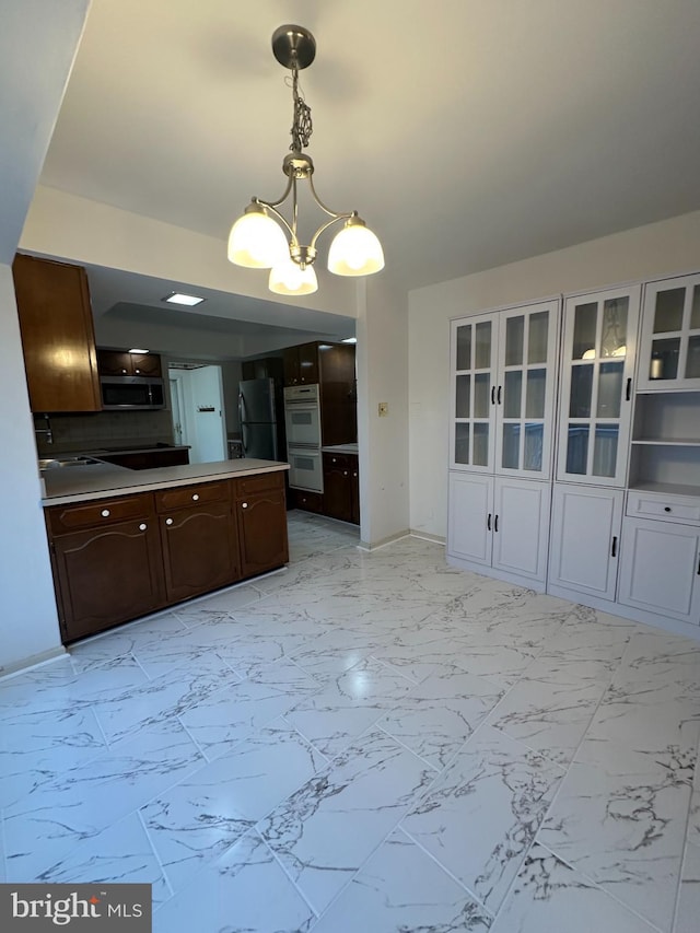 kitchen featuring dark brown cabinetry, stainless steel microwave, freestanding refrigerator, marble finish floor, and double oven