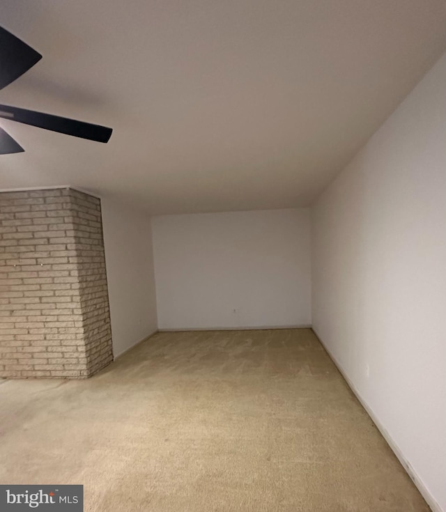 bonus room featuring a ceiling fan, light carpet, and brick wall