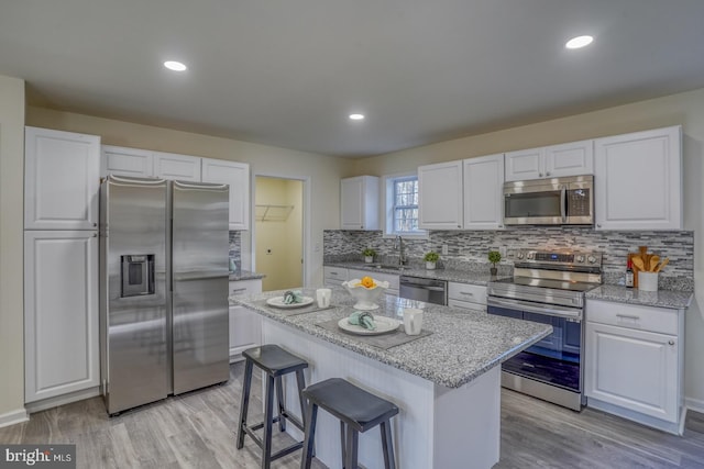 kitchen featuring light hardwood / wood-style floors, white cabinets, a kitchen island, and stainless steel appliances