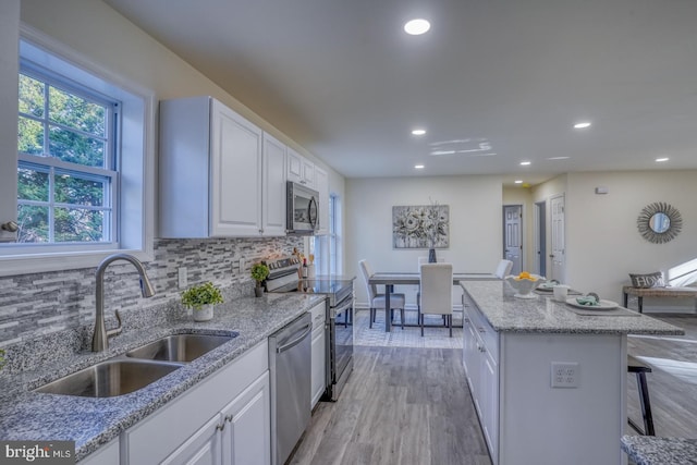 kitchen with white cabinetry, light hardwood / wood-style flooring, appliances with stainless steel finishes, sink, and tasteful backsplash