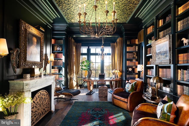 sitting room with built in shelves, hardwood / wood-style floors, a chandelier, and ornamental molding