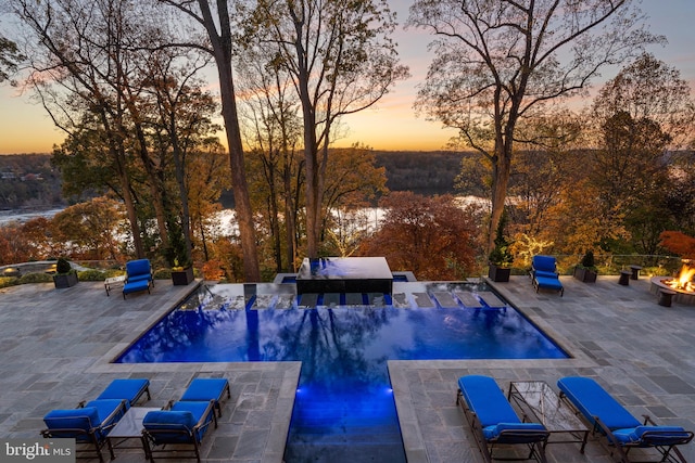 pool at dusk with a patio and grilling area