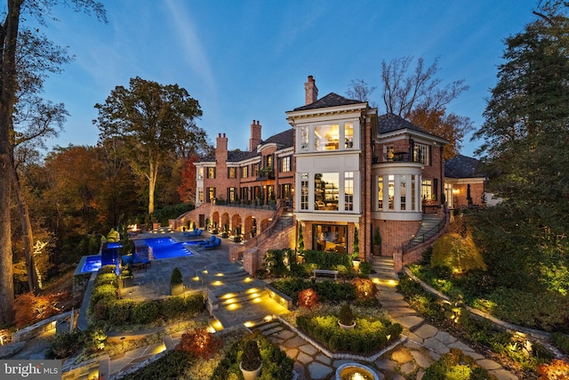 back house at dusk featuring a patio