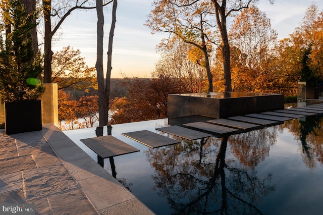 patio terrace at dusk featuring a water view