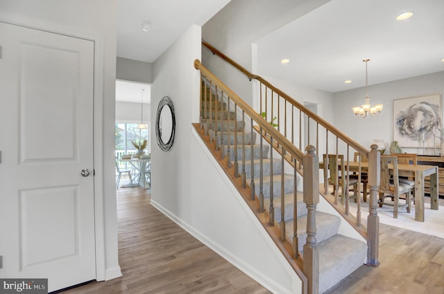 staircase with recessed lighting, wood finished floors, baseboards, and an inviting chandelier