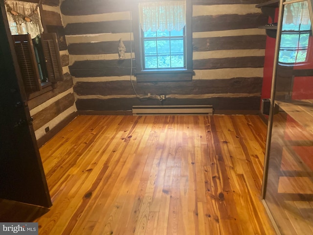 interior space with wood-type flooring and a baseboard heating unit