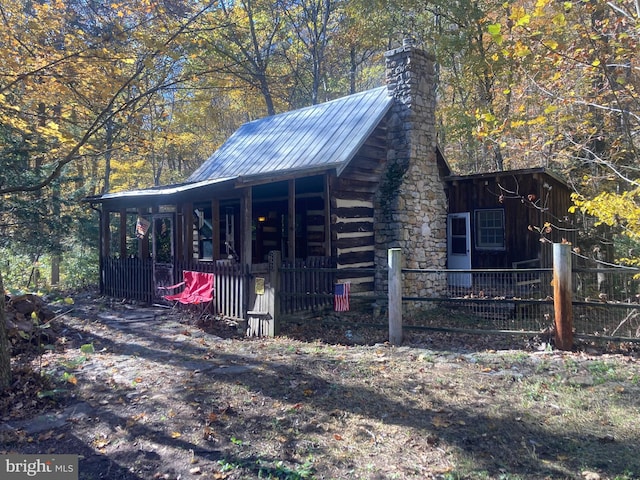 view of outbuilding featuring fence and covered porch
