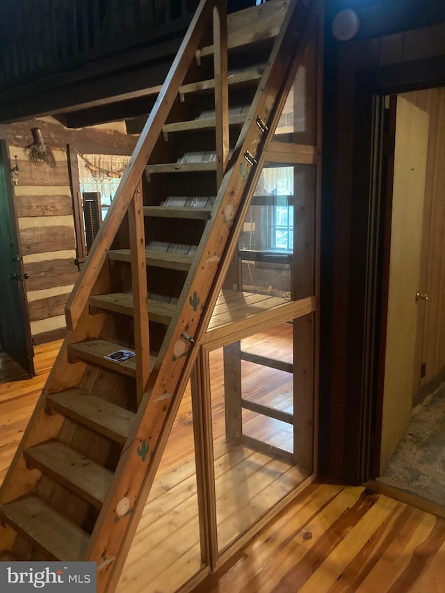 staircase with hardwood / wood-style floors and wooden walls