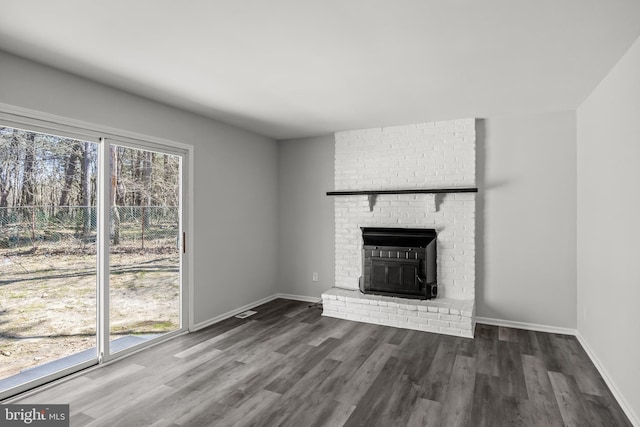 unfurnished living room with a brick fireplace, brick wall, and wood-type flooring