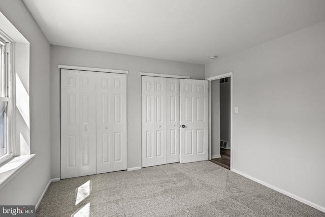 unfurnished bedroom featuring carpet and two closets