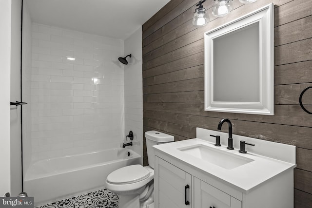 full bathroom with wood walls, vanity with extensive cabinet space, toilet, tile floors, and tub / shower combination