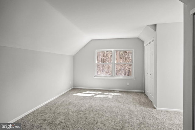 bonus room with carpet flooring and vaulted ceiling