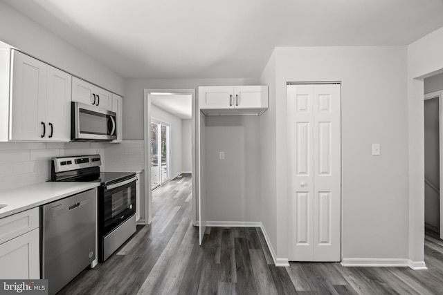 kitchen with dark hardwood / wood-style floors, stainless steel appliances, white cabinets, and backsplash