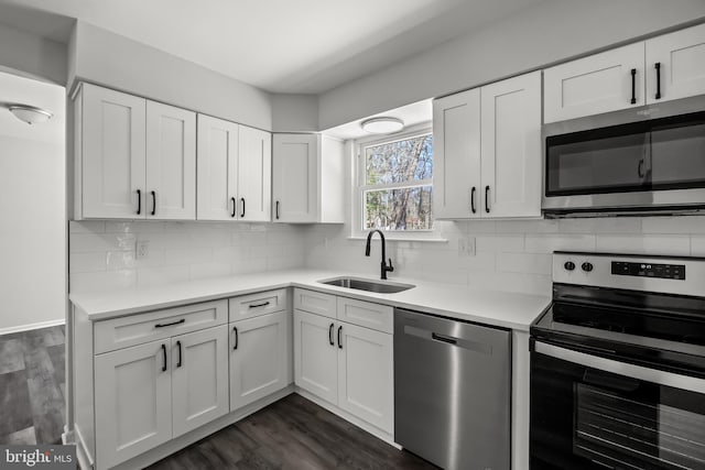 kitchen with dark hardwood / wood-style floors, tasteful backsplash, stainless steel appliances, sink, and white cabinetry